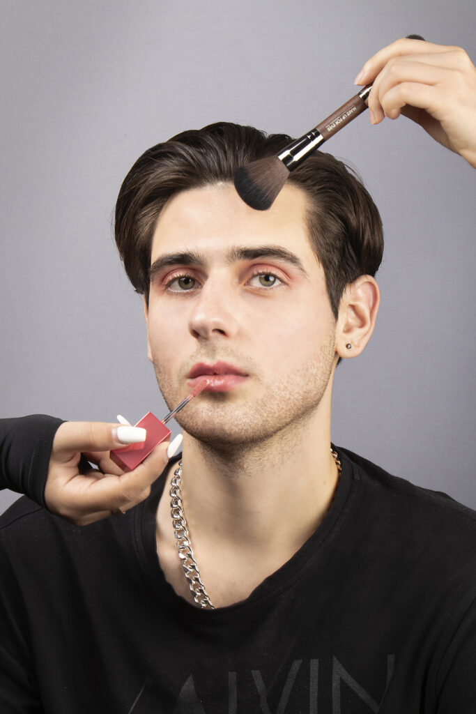 A male model is putting on makeup